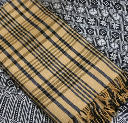 A brown cotton khes with a plaid pattern laid out on a surface with a geometric patterned fabric in the background.