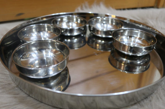 Stainless steel tray with multiple small bowls on a light background