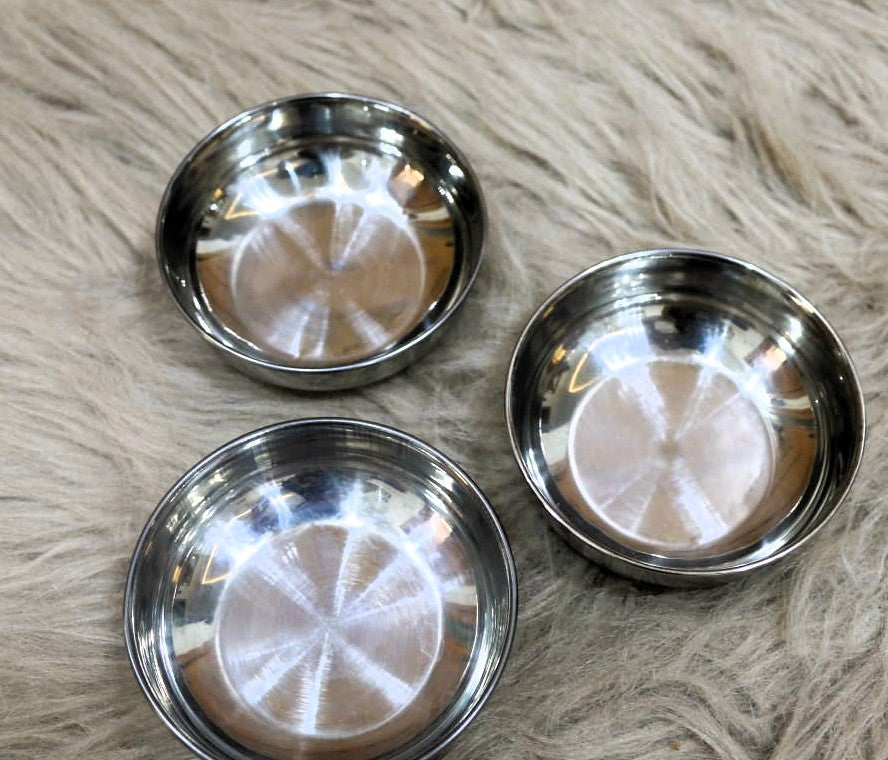 Three stainless steel bowls on a textured surface