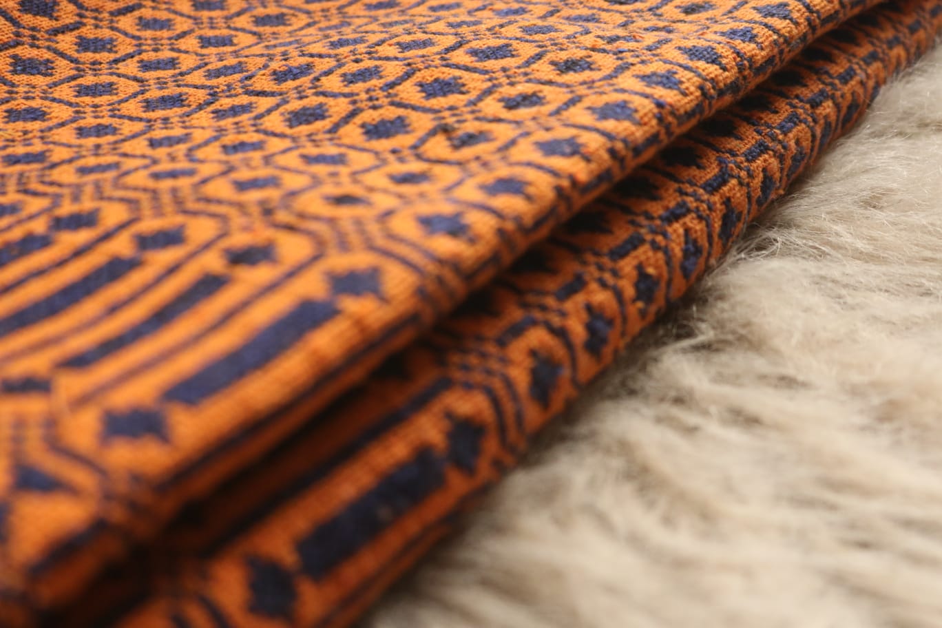 Folded fabric with orange and blue pattern on a textured surface