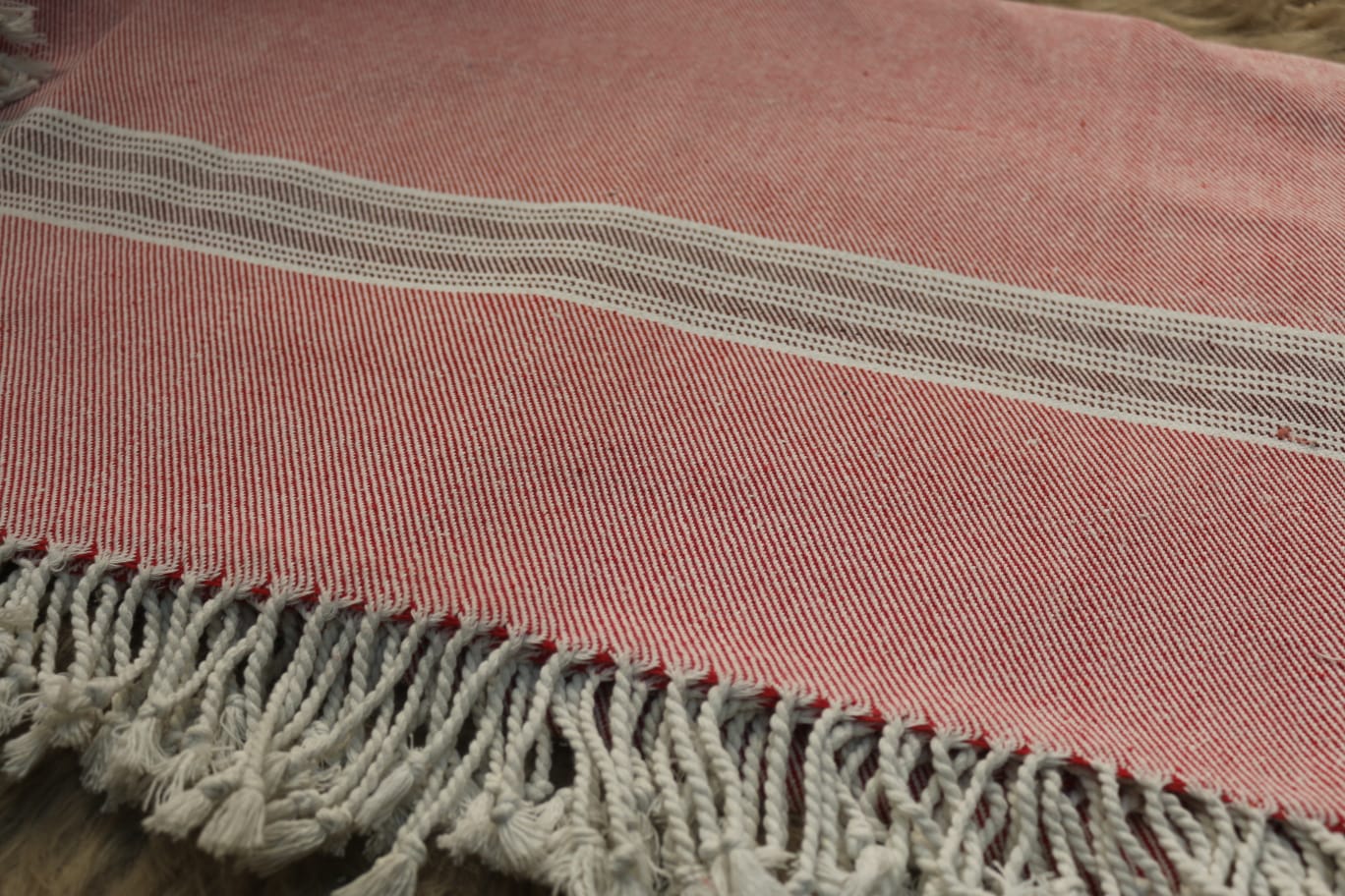 Close-up of a pink woven fabric with white stripes and fringes.