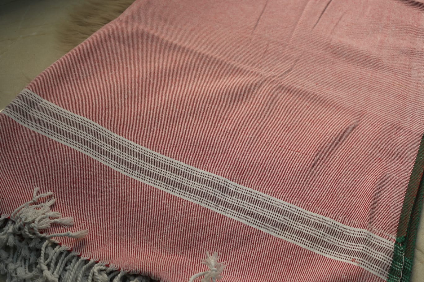 Pink fabric with a striped pattern and fringes on a plain background