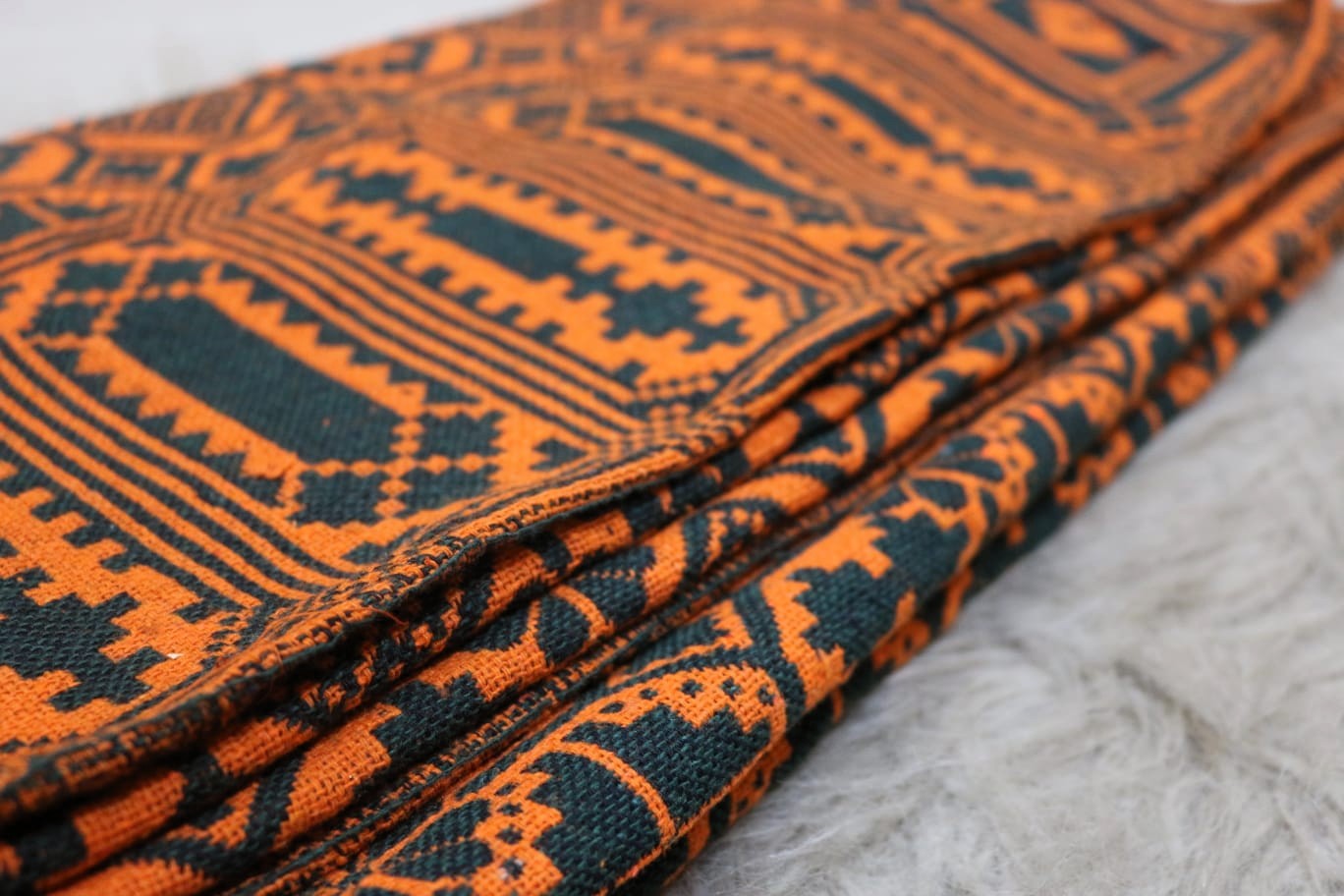 Close-up of orange and black patterned fabric on a textured surface