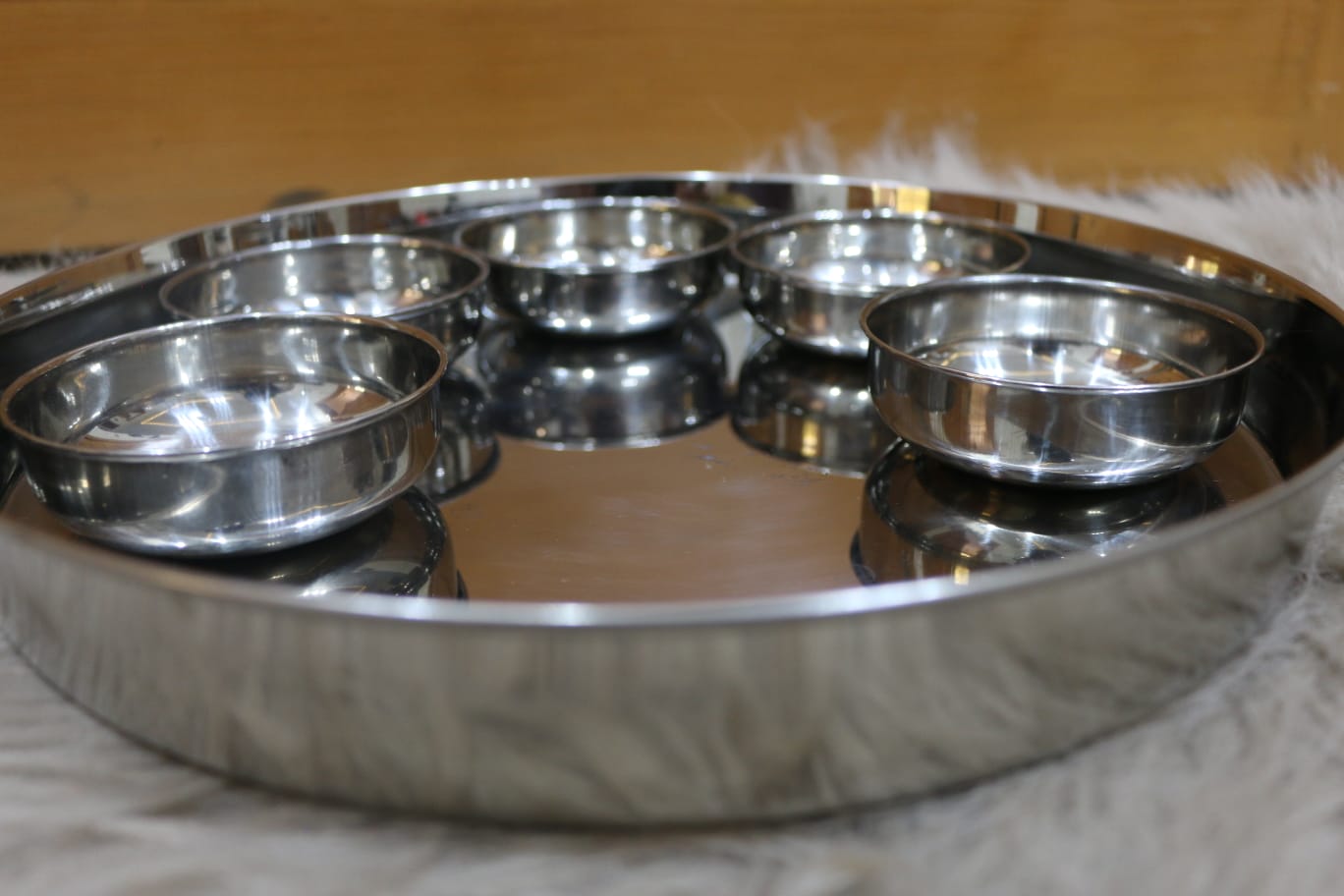 Set of stainless steel bowls and tray on a wooden surface