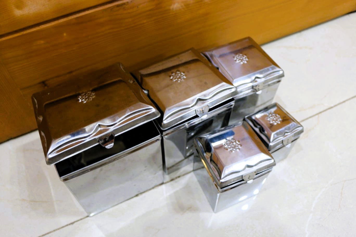 Set of silver jewelry/storage boxes on a marble surface with wooden background