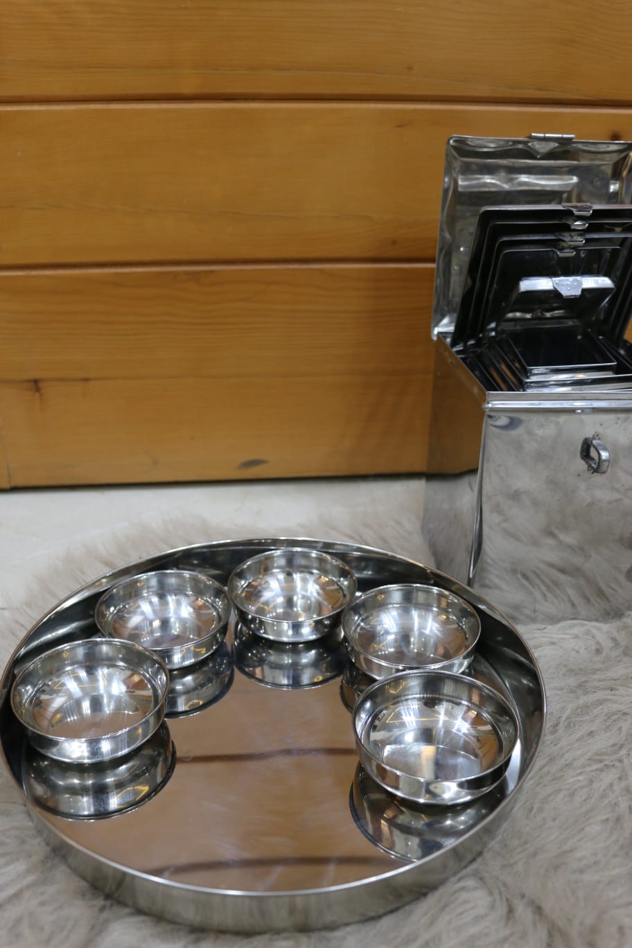 Set of stainless steel dishes on a tray with a wooden background