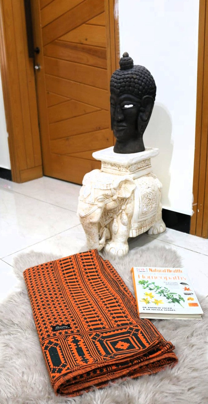 Decorative khes/khais with intricate patterns on a textured surface, with a black Buddha statue and white elephant sculpture in the background.