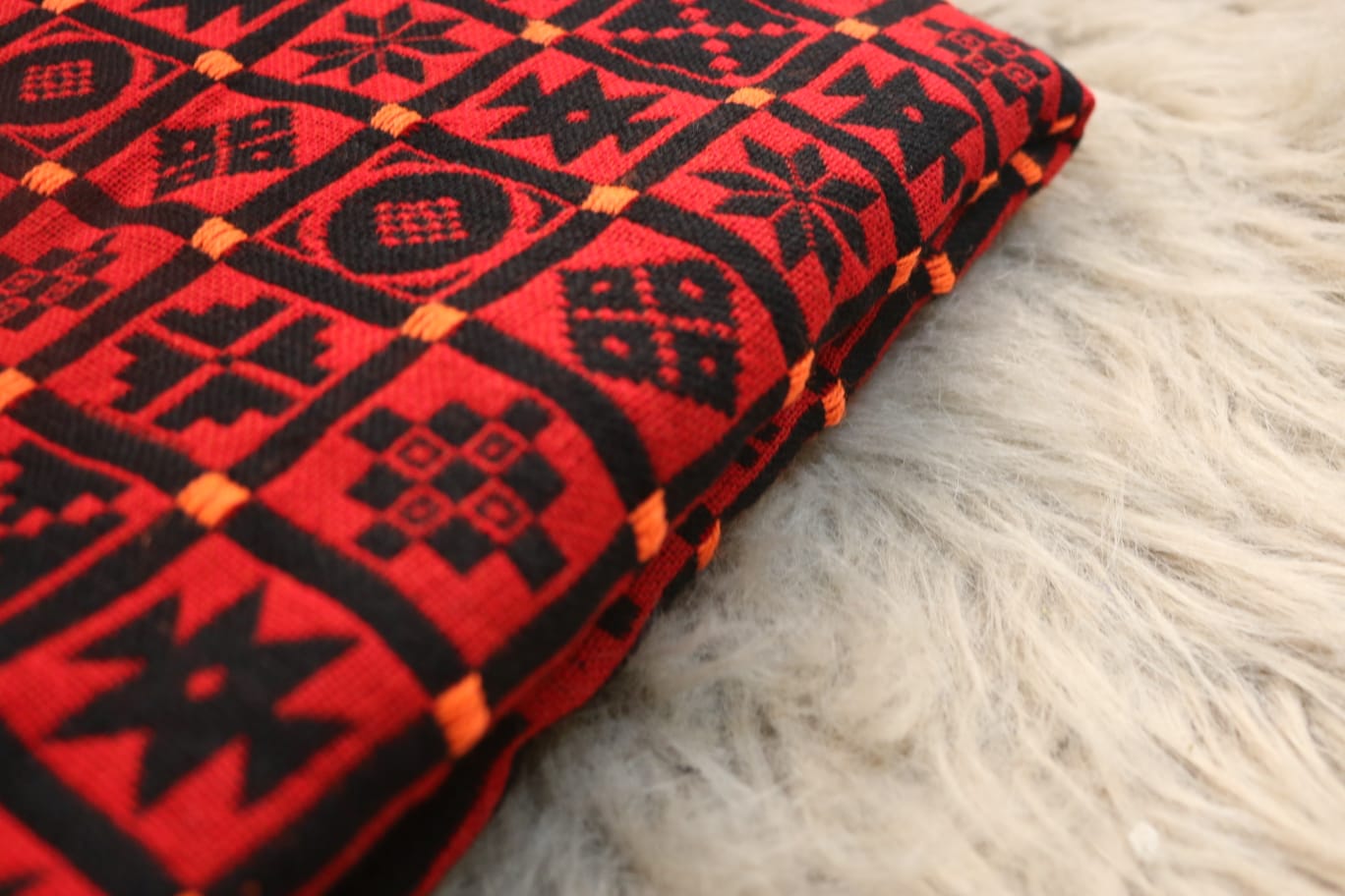 Red and black patterned fabric on a white fur surface