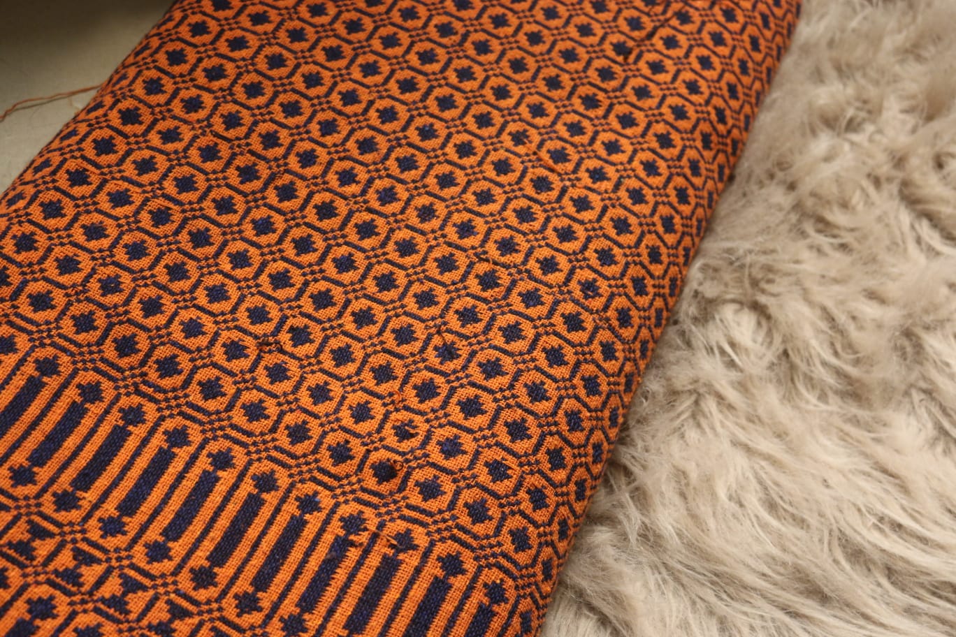 Close-up of orange and black patterned fabric on a textured surface