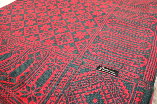 Red and black patterned Khes fabric with a brand label on a textured background