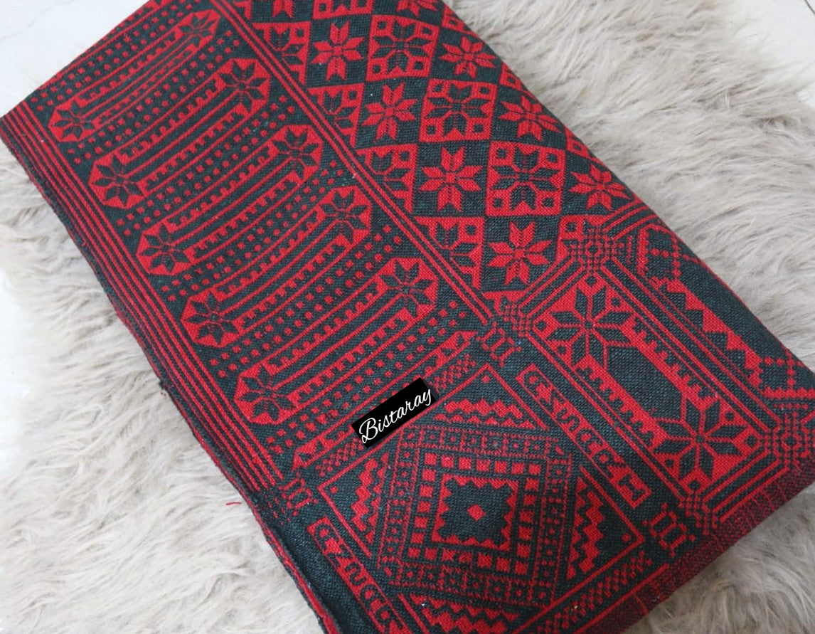 Red and black patterned Khes fabric on a white fluffy surface